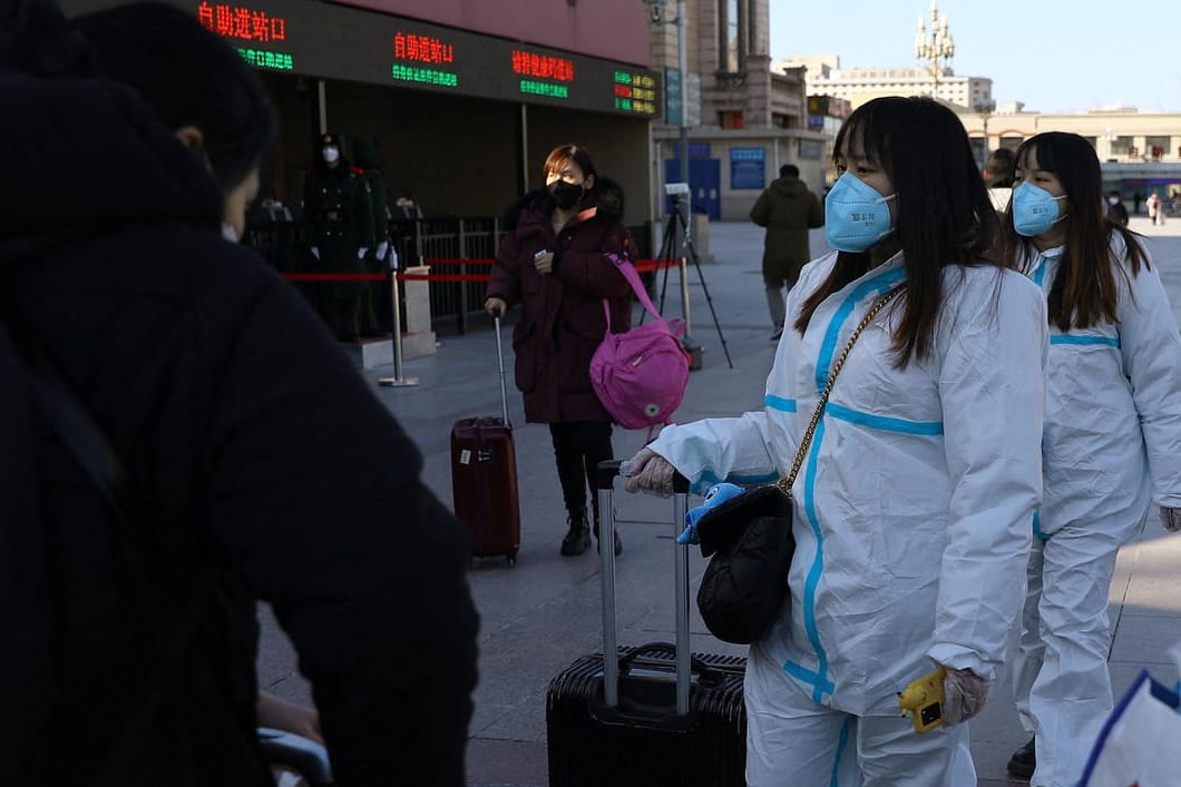 Beijing kurz vor dem Fest: Frauen in Schutzanzügen sind auf dem Weg zum Bahnhof.