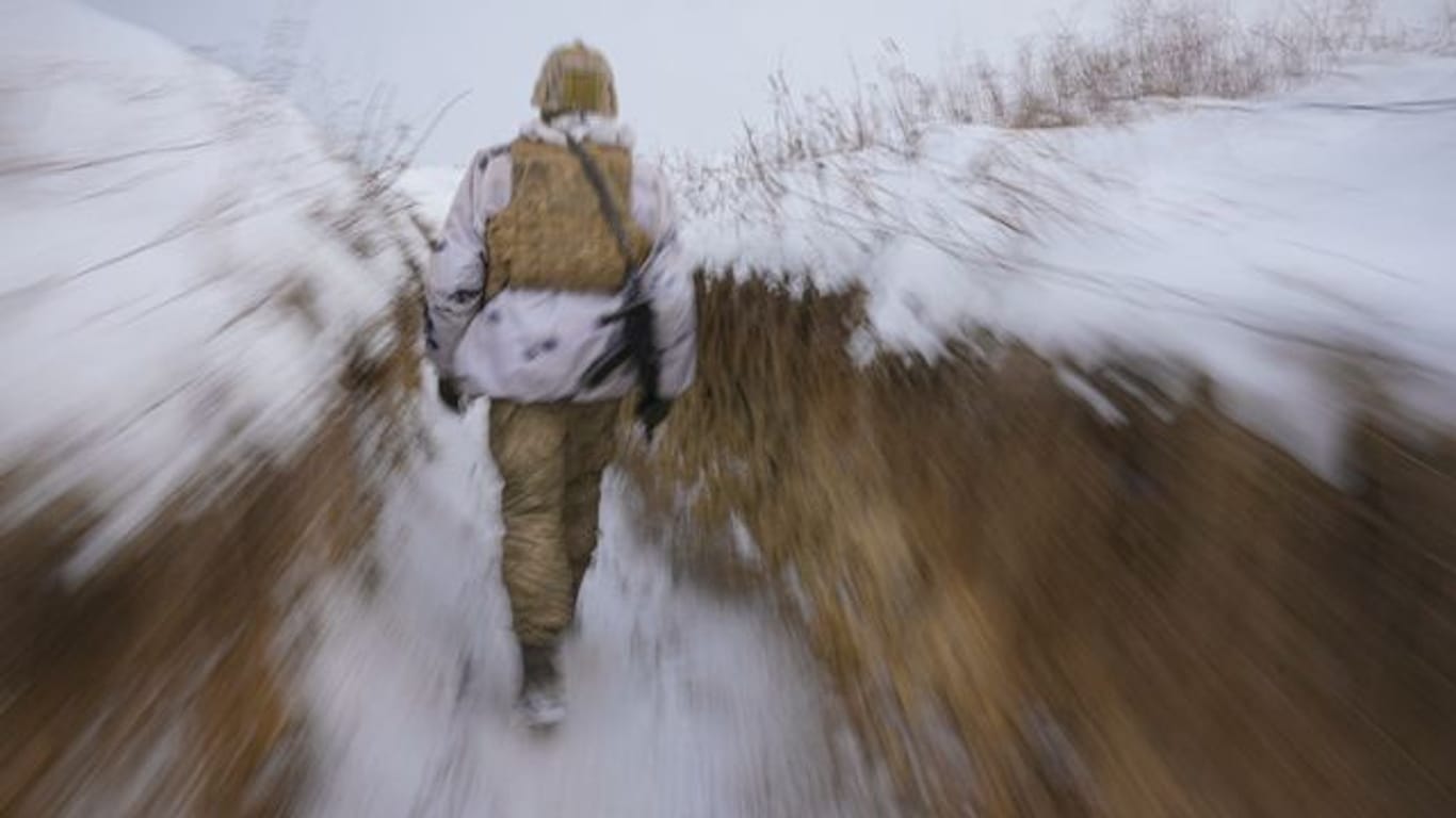 Ein ukrainischer Soldat geht an der Frontlinie durch einen Graben.