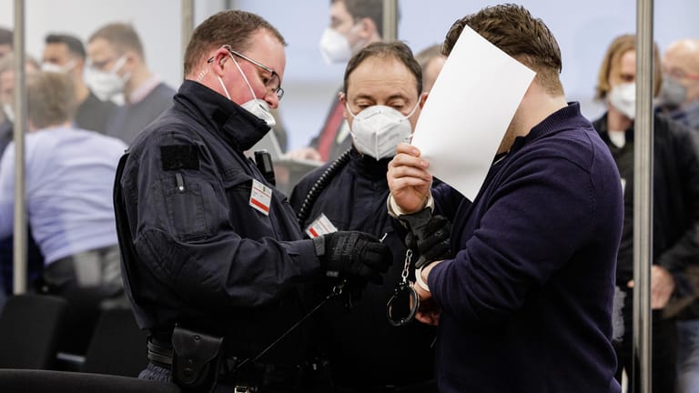 Prozessbeginn in Dresden: Ein Angeklagter verdeckt sein Gesicht.