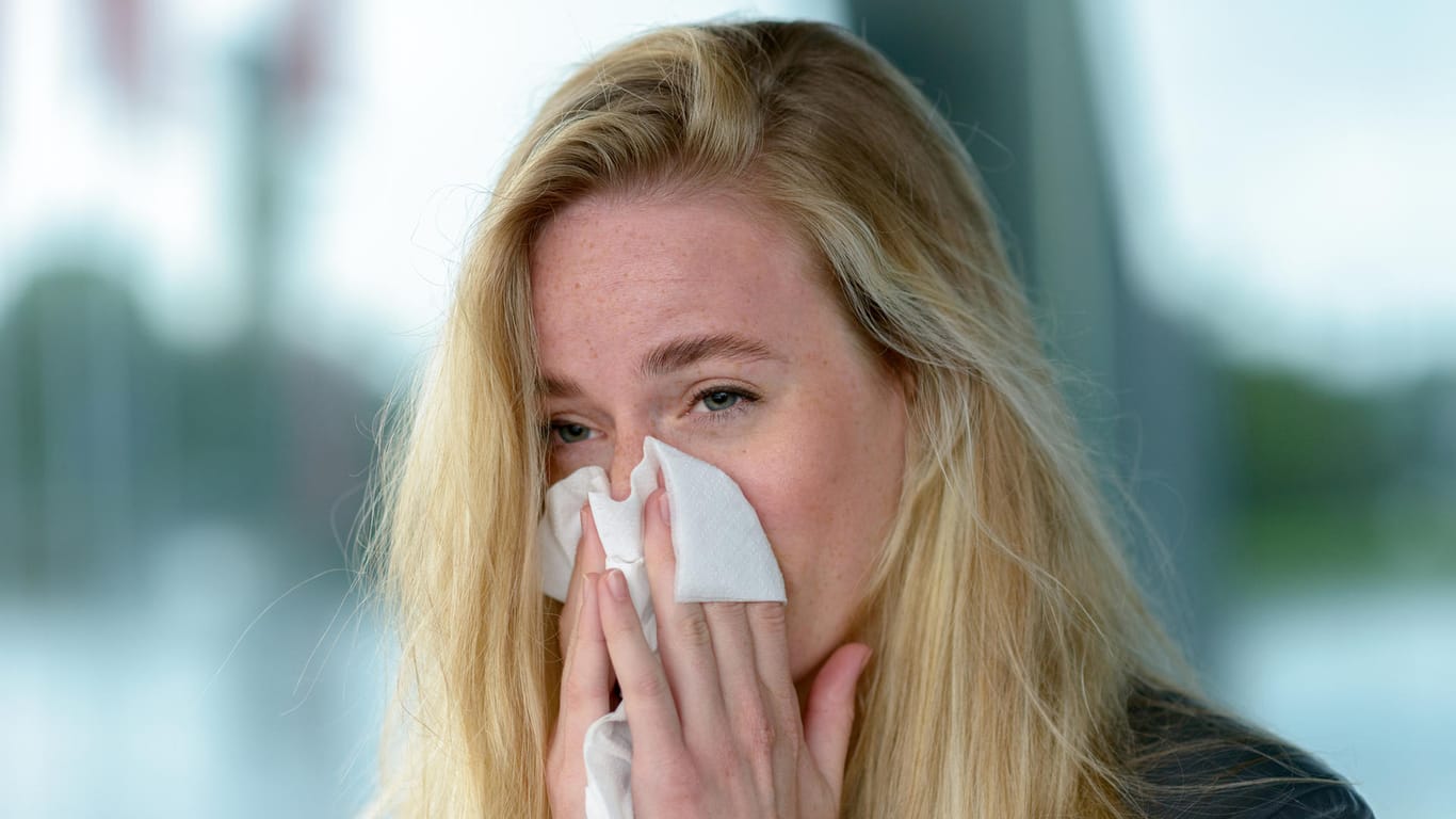 Junge Frau schnäuzt sich die Nase. Umweltverschmutzung und milde Winter tragen dazu bei, dass die Pollen immer früher fliegen und Allergiker nur noch eine kurze winterliche Verschnaufpause haben.