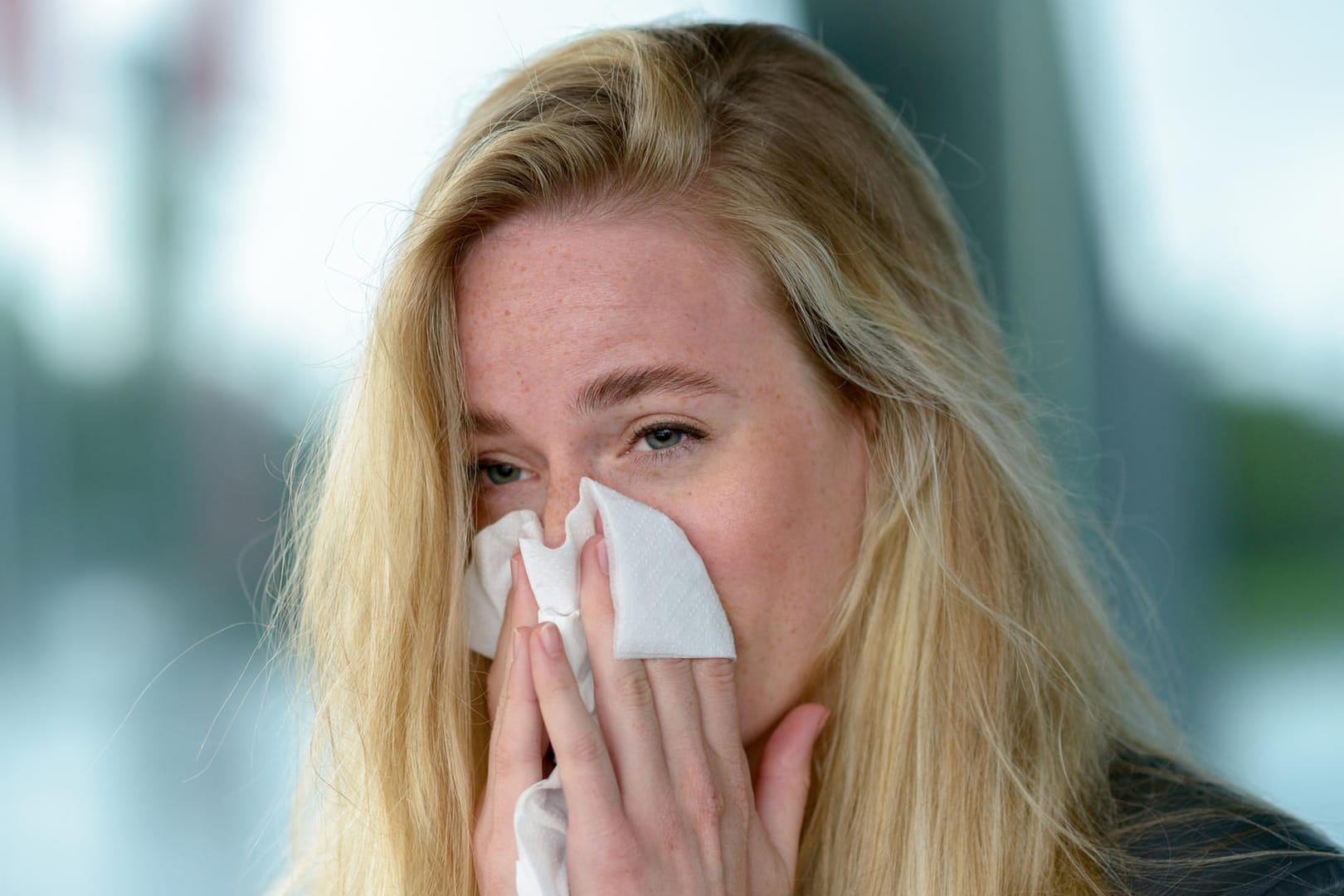 Junge Frau schnäuzt sich die Nase. Umweltverschmutzung und milde Winter tragen dazu bei, dass die Pollen immer früher fliegen und Allergiker nur noch eine kurze winterliche Verschnaufpause haben.