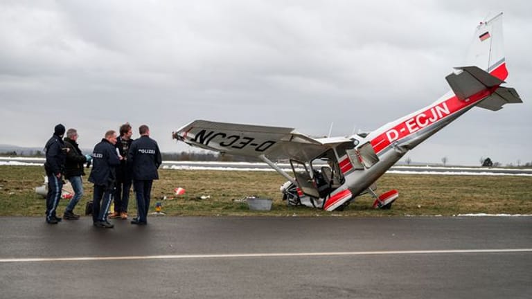 Die ermittelnden Polizeibeamten stehen neben dem verunglücktem Kleinflugzeug Cessna auf dem Flugplatz in Coburg.