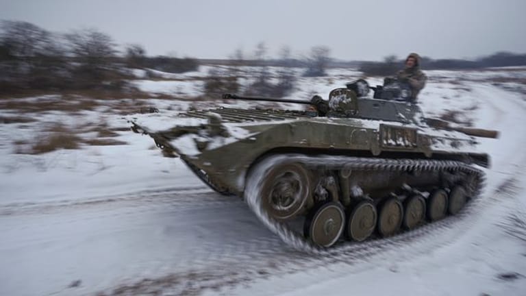 Ukrainische Soldaten fahren mit einem gepanzerten Mannschaftstransportwagen durch den Schnee.