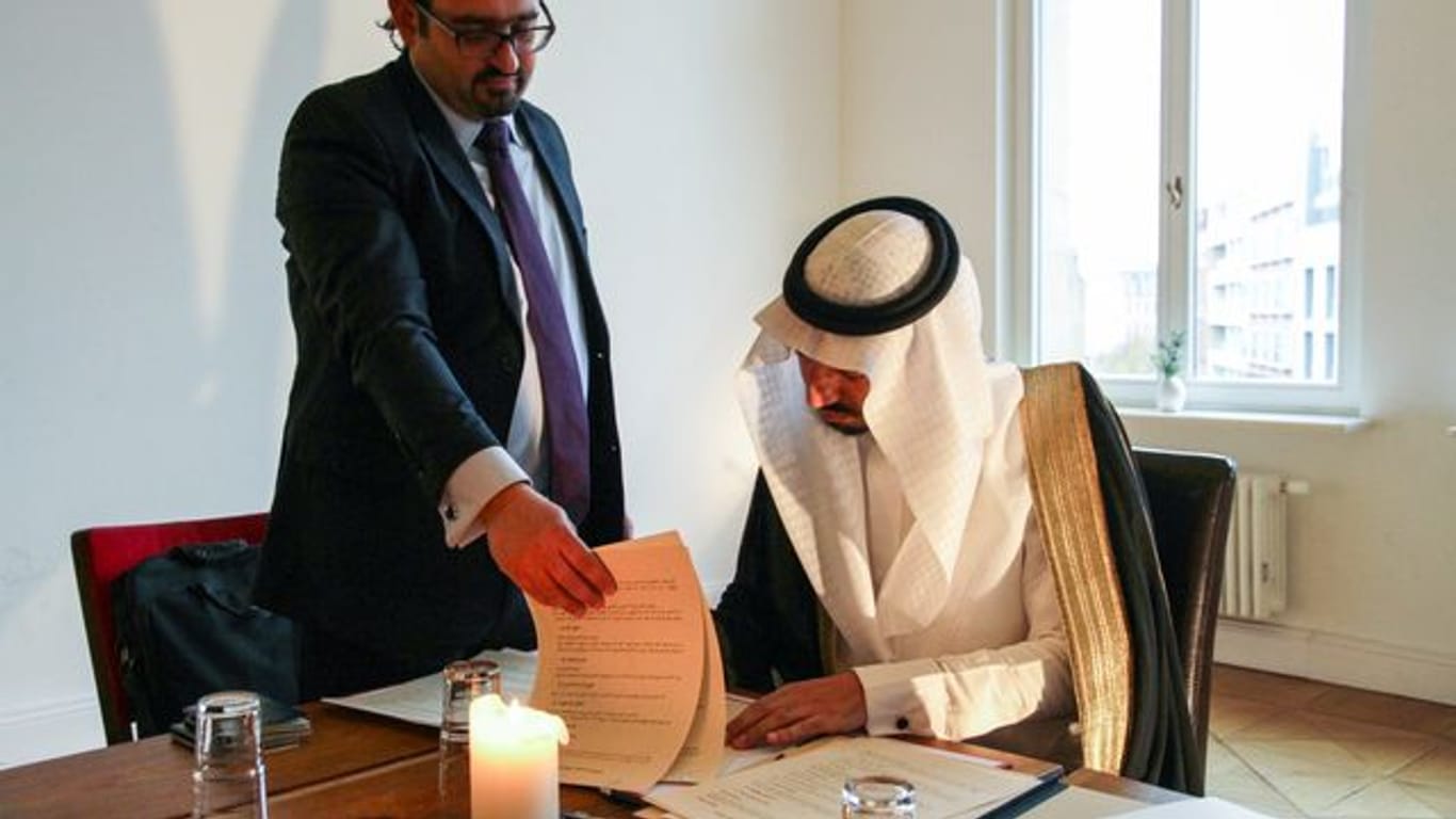 Prinz Mulham al-Schibli vom Fawara-Stamm aus Syrien beim Unterzeichnen des "Verhaltenskodex für ein syrisches Zusammenleben", der deutsch-syrische Verfassungsrechtler Naseef Naeem assistiert.