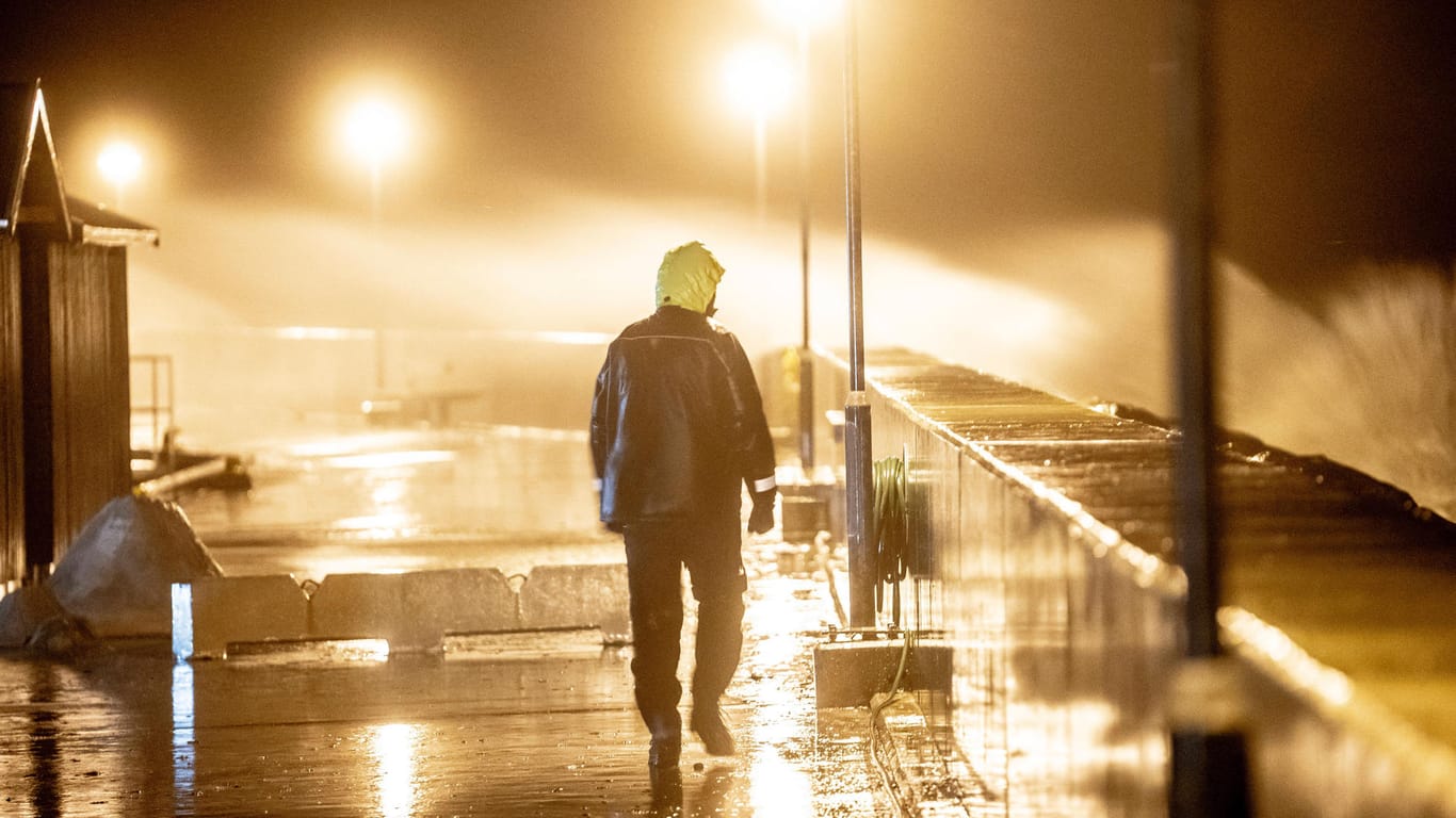 Ein Mann geht am Ufer von Hundested in Dänemark spazieren: Hohe Wellen, verursacht durch den Sturm Malik, schlagen an die Hafenmauern.