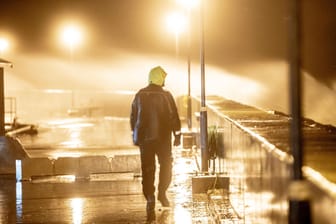 Ein Mann geht am Ufer von Hundested in Dänemark spazieren: Hohe Wellen, verursacht durch den Sturm Malik, schlagen an die Hafenmauern.