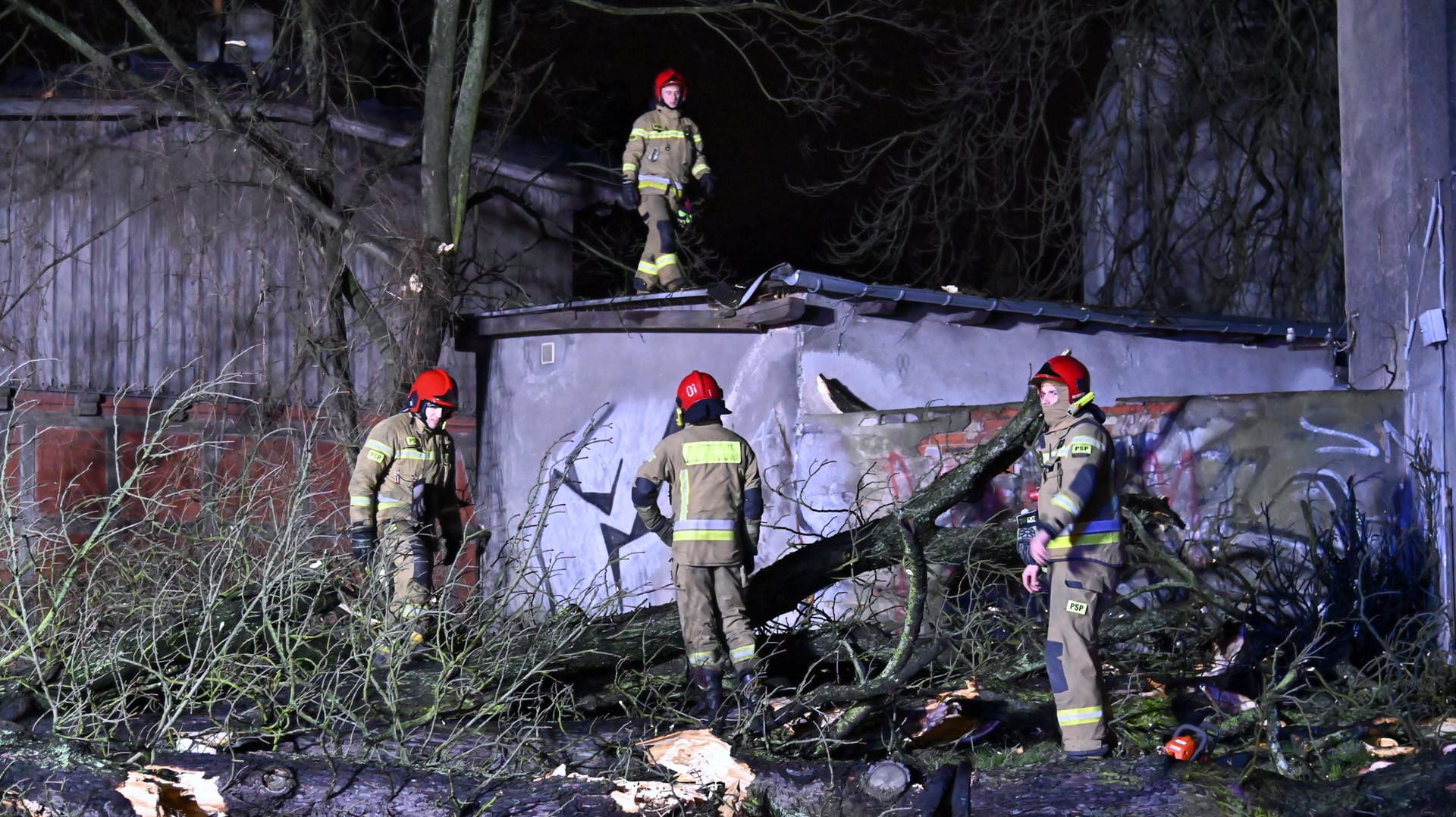 Sturmschäden in Polen: Feuerwehrleute räumen eine Straße, die durch einen umgestürzten Baum blockiert ist.