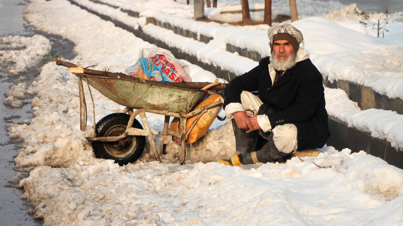 Winter in Afghanistan: Ein Mann sitzt in Kabul im Schnee und wartet auf einen Job als Tagelöhner.