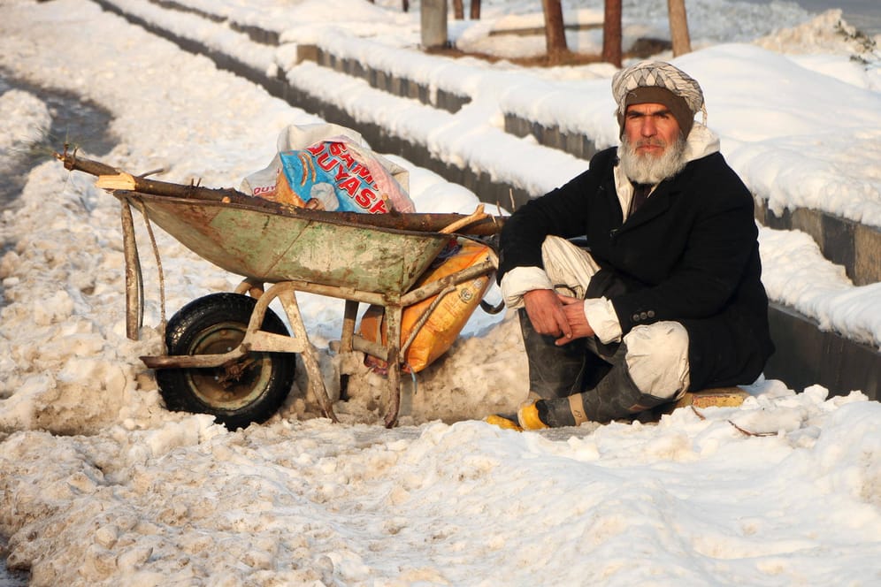 Winter in Afghanistan: Ein Mann sitzt in Kabul im Schnee und wartet auf einen Job als Tagelöhner.