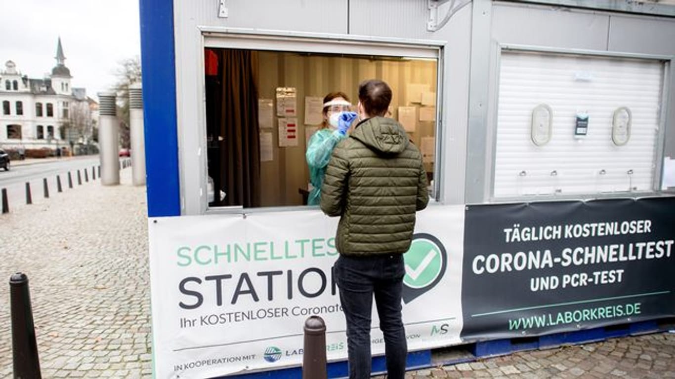 Eine Mitarbeiterin einer Teststation in der Oldenburger Innenstadt nimmt einen Abstrich von einem jungen Mann.