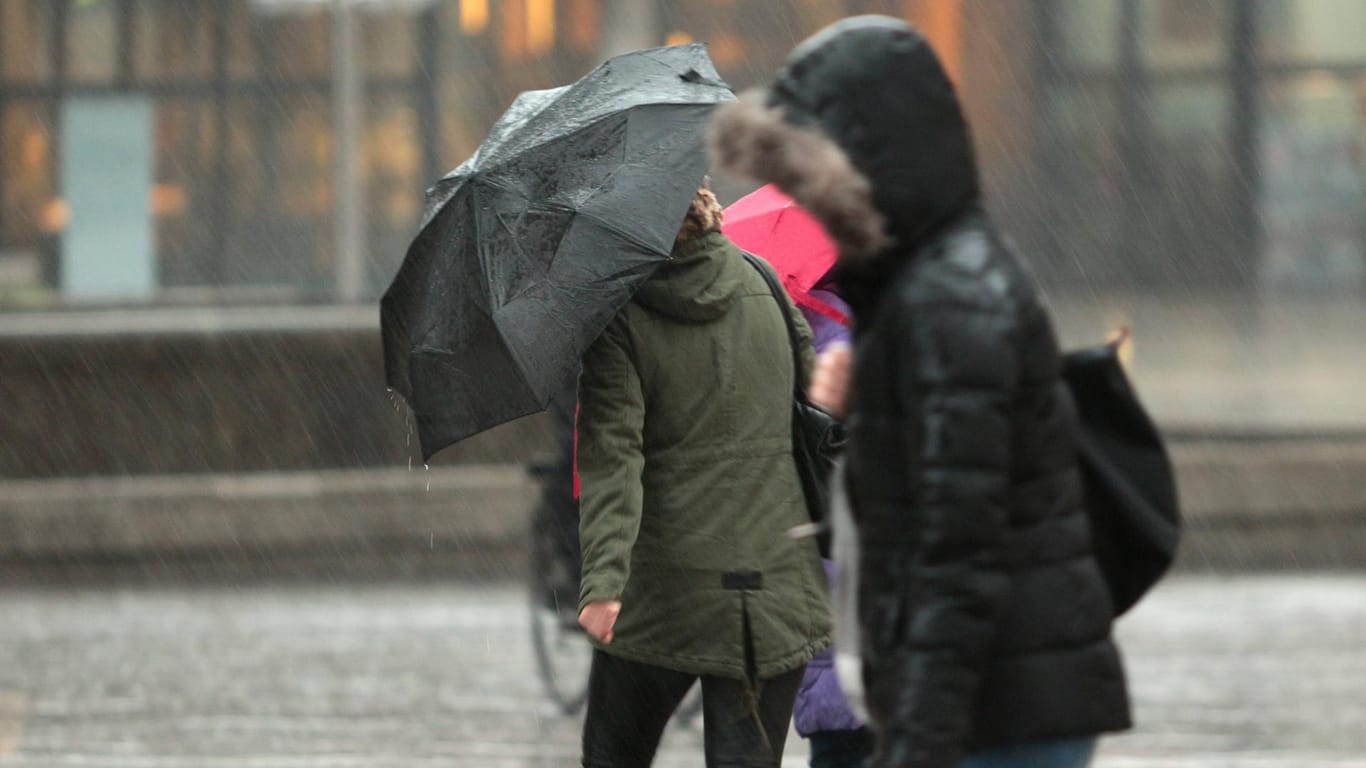Passantinnen mit Regenschirm (Symbolbild): In Köln soll es den Tag über Sturmböen geben.
