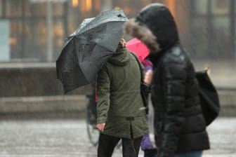 Passantinnen mit Regenschirm (Symbolbild): In Köln soll es den Tag über Sturmböen geben.