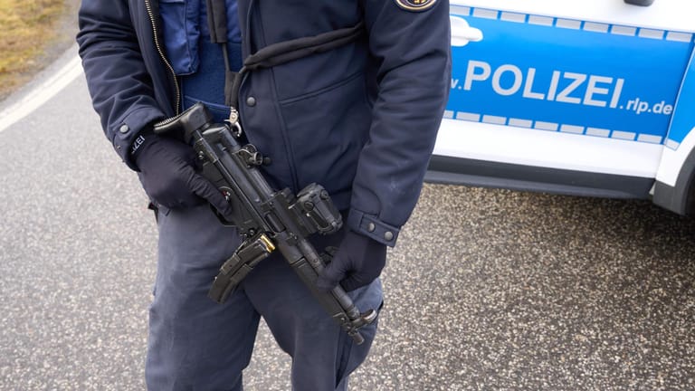 Ein schwer bewaffneter Polizist bewacht einen Tatort in Rheinland-Pfalz: Im Landkreis Kusel haben offenbar mehrere Täter eine Polizistin und einen Polizisten bei einer Verkehrskontrolle erschossen.