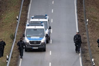 Polizisten suchen eine Straße in der Nähe des Tatorts ab