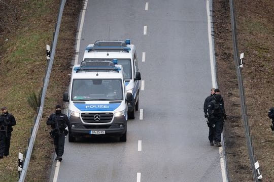 Polizisten suchen eine Straße in der Nähe des Tatorts ab