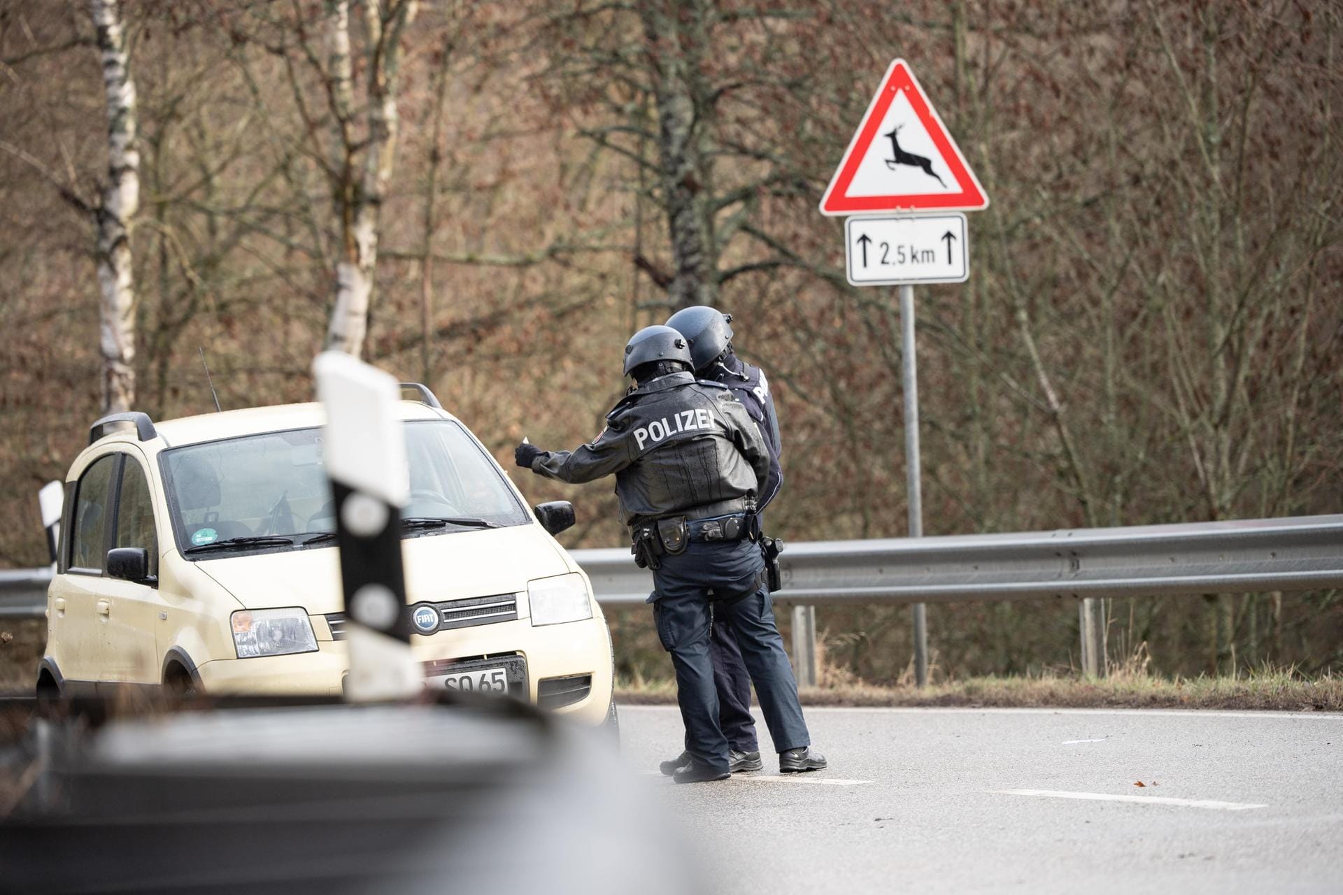Polizeibeamte kontrollieren an einer Absperrung an der Kreisstraße 22, rund einen Kilometer von dem Tatort entfernt, ein Auto: Die tödlichen Schüsse fielen bei einer routinemäßigen Verkehrskontrolle.
