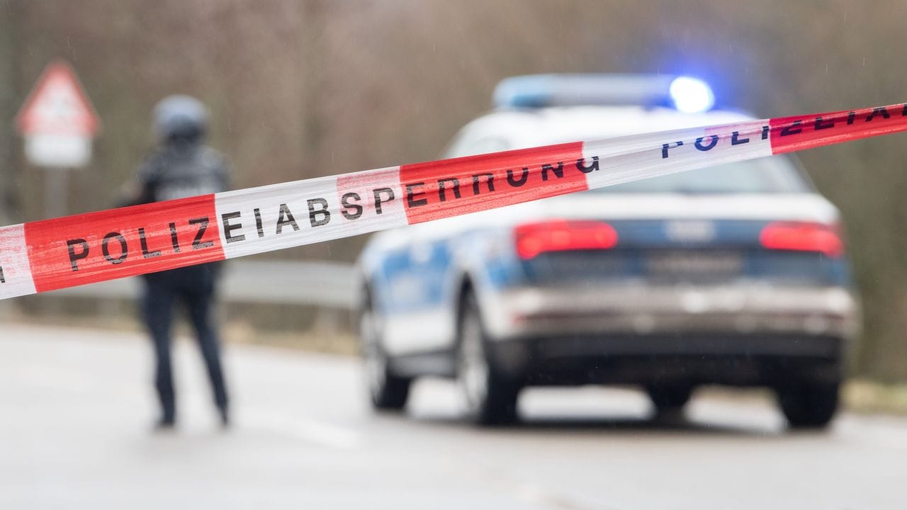 Schwerbewaffnete Polizisten stehen an einer Straßensperre.