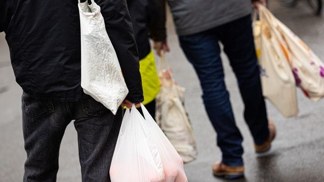Passanten gehen mit Einkaufstüten über einen Markt