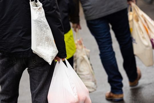 Passanten gehen mit Einkaufstüten über einen Markt