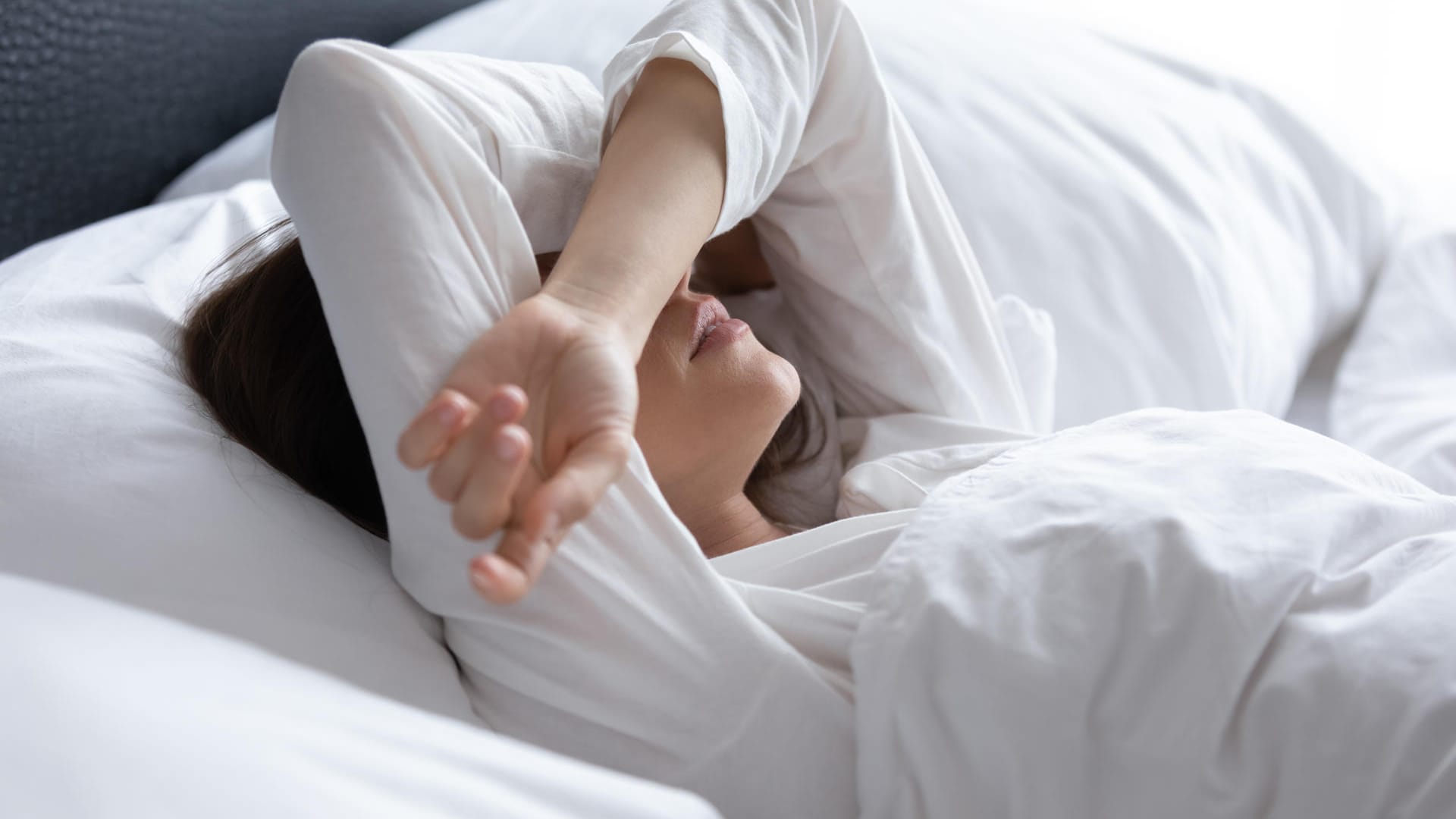 Frau liegt wach im Bett. Viele Menschen liegen oft lange Zeit wach, bis sie endlich einschlafen.