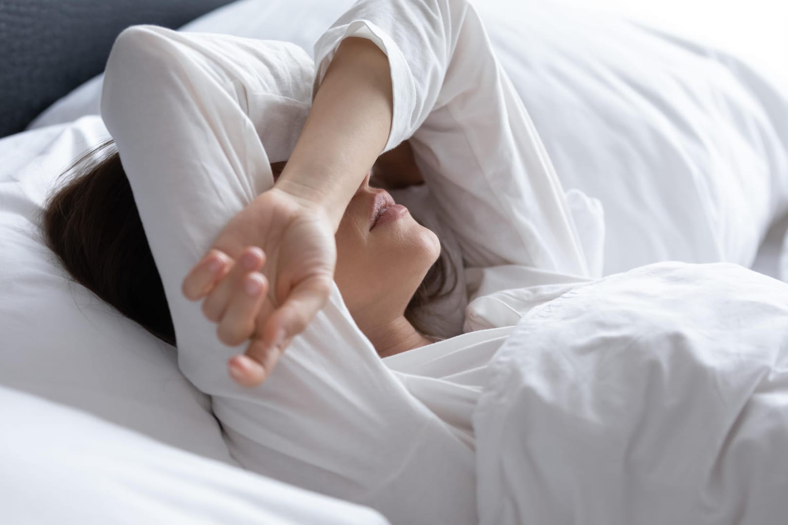 Frau liegt wach im Bett. Viele Menschen liegen oft lange Zeit wach, bis sie endlich einschlafen.