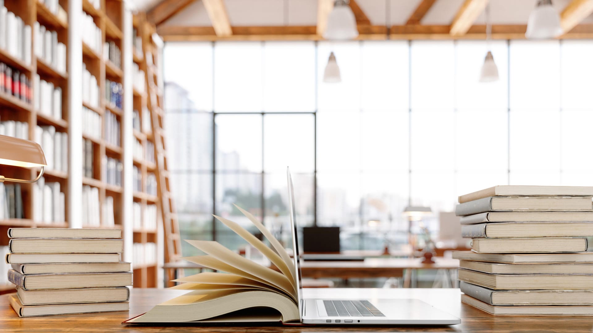 Ein offenes Buch und ein Laptop in einer Bibliothek.