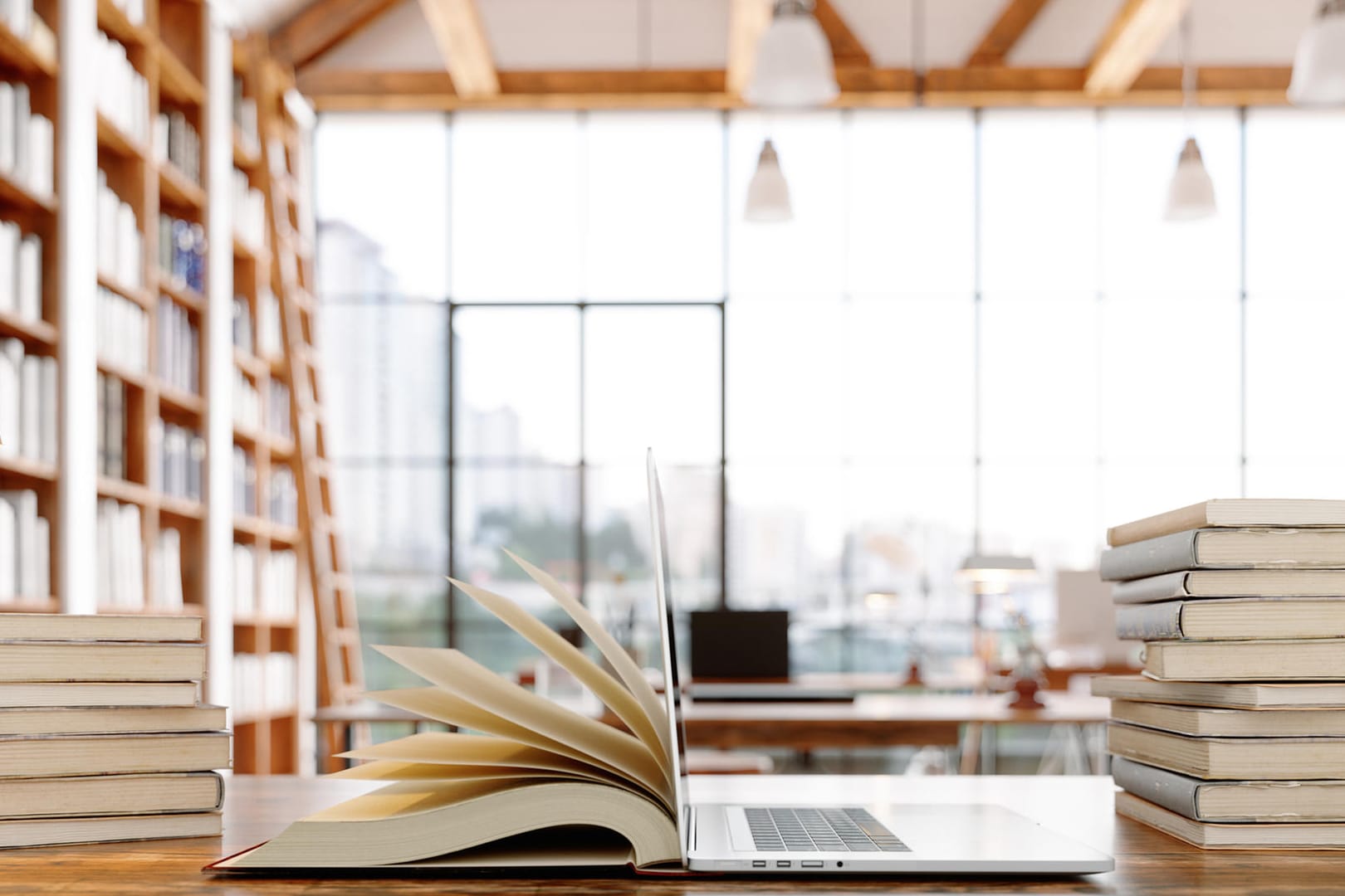 Ein offenes Buch und ein Laptop in einer Bibliothek.