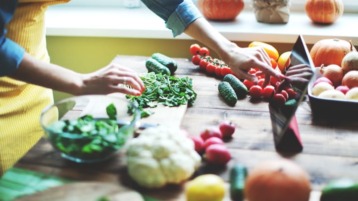 Ein Frau kocht viel frisches Gemüse nach Rezept