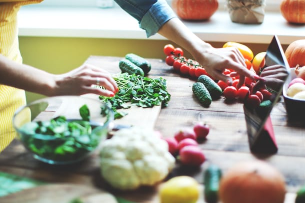 Ein Frau kocht viel frisches Gemüse nach Rezept