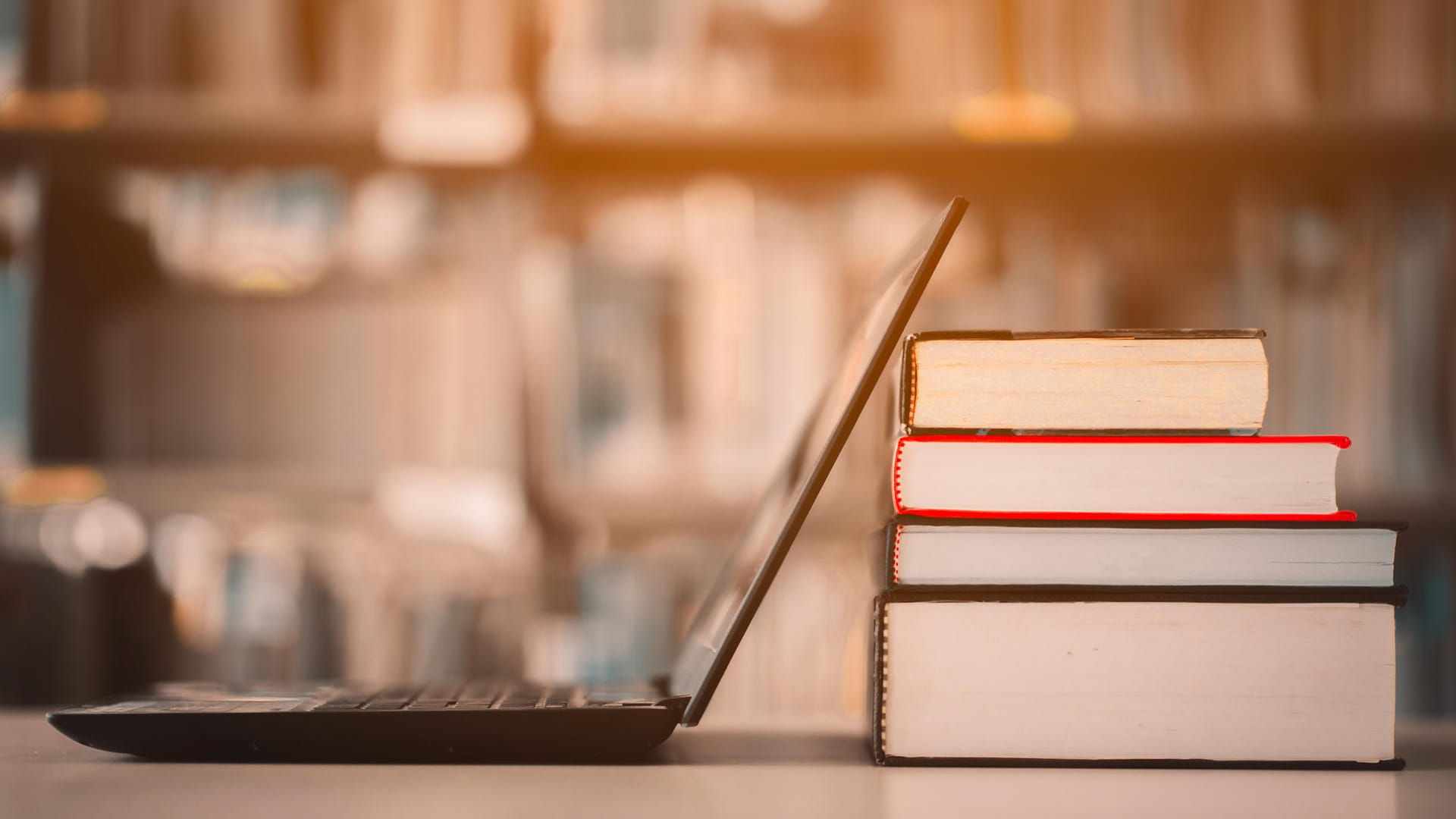 Bookshelves and laptops are placed on the library desk.E-learning class and e-book digital technology