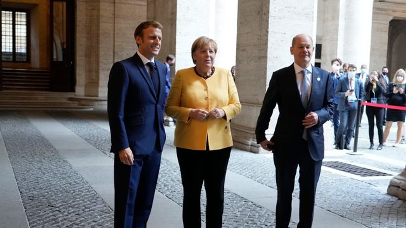 Emmanuel Macron (l-r), Präsident von Frankreich, begrüßt Angela Merkel (CDU), geschäftsführende Bundeskanzlerin, und Olaf Scholz (SPD), Bundesfinanzminister und Kanzlerkandidat, vor einem Treffen der Europäischen Union und der Afrikanischen Union in der französischen Botschaft.