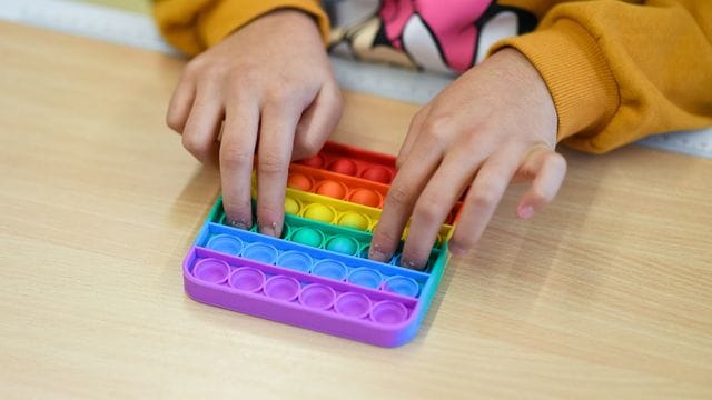 In einem Klassenzimmer einer Bielefelder Grundschule spielt ein Kind mit Pop-Its. In einem Klassenzimmer einer Bielefelder Grundschule spielt ein Kind mit Pop-Its.