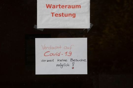 "Warteraum Testung" und "Verdacht auf Covid-19 derzeit keine Besuche möglich!" steht auf Zetteln an einer Scheibe in dem Seniorenheim, in dem es zum Corona-Ausbruch gekommen ist.