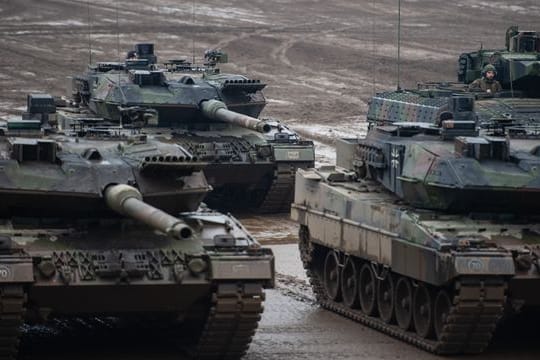 Drei Kampfpanzer der Bundeswehr vom Typ Leopard 2A6 und ein Schützenpanzer vom Typ Puma stehen bei einer Übung im Gelände.
