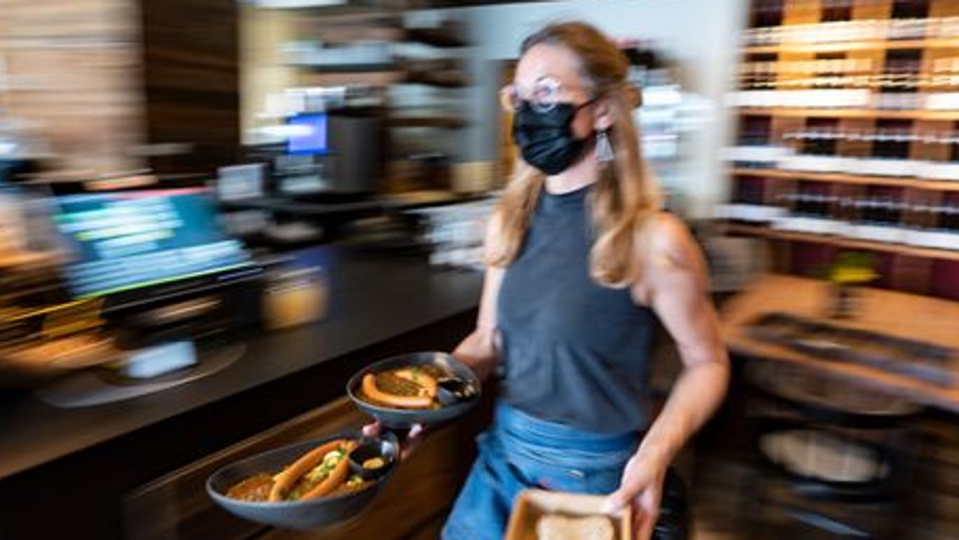 Eine Kellnerin trägt in einem Restaurant Essensteller.