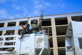Bewaffnete Tigray-Streitkräfte begleiten gefangene äthiopische Regierungssoldaten und verbündete Milizangehörige in offenen Lastwagen in eine Haftanstalt.