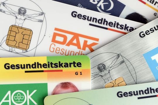 Gesundheitskarten verschiedener Krankenkassen liegen auf einem Tisch.