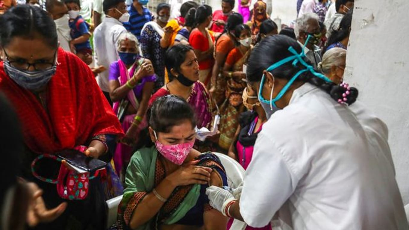 Eine Mitarbeiterin des Gesundheitswesens verabreicht eine Dosis mit dem Corona-Impfstoff Covaxin, während Hunderte von Menschen anstehen, um ihre zweite Dosis des Impfstoffs im städtischen Stadion in Hyderabad zu erhalten.