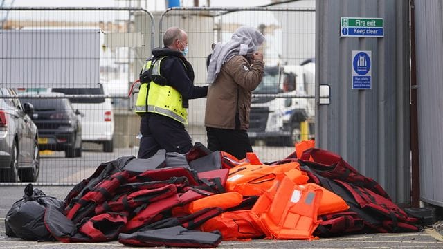 Ein Flüchtling wird von Beamten der Grenzpolizei nach Dover in Kent gebracht. Ein Flüchtling wird von Beamten der Grenzpolizei nach Dover in Kent gebracht.