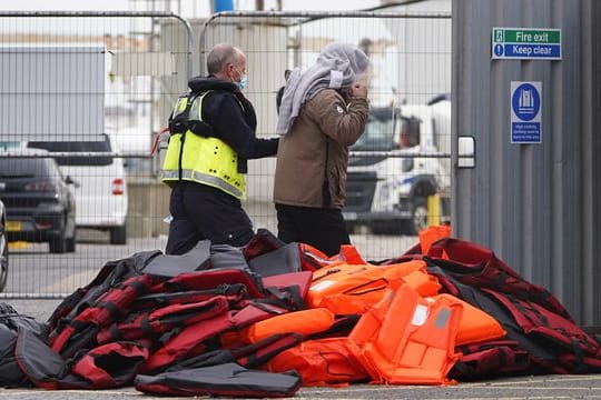 Ein Flüchtling wird von Beamten der Grenzpolizei nach Dover in Kent gebracht.