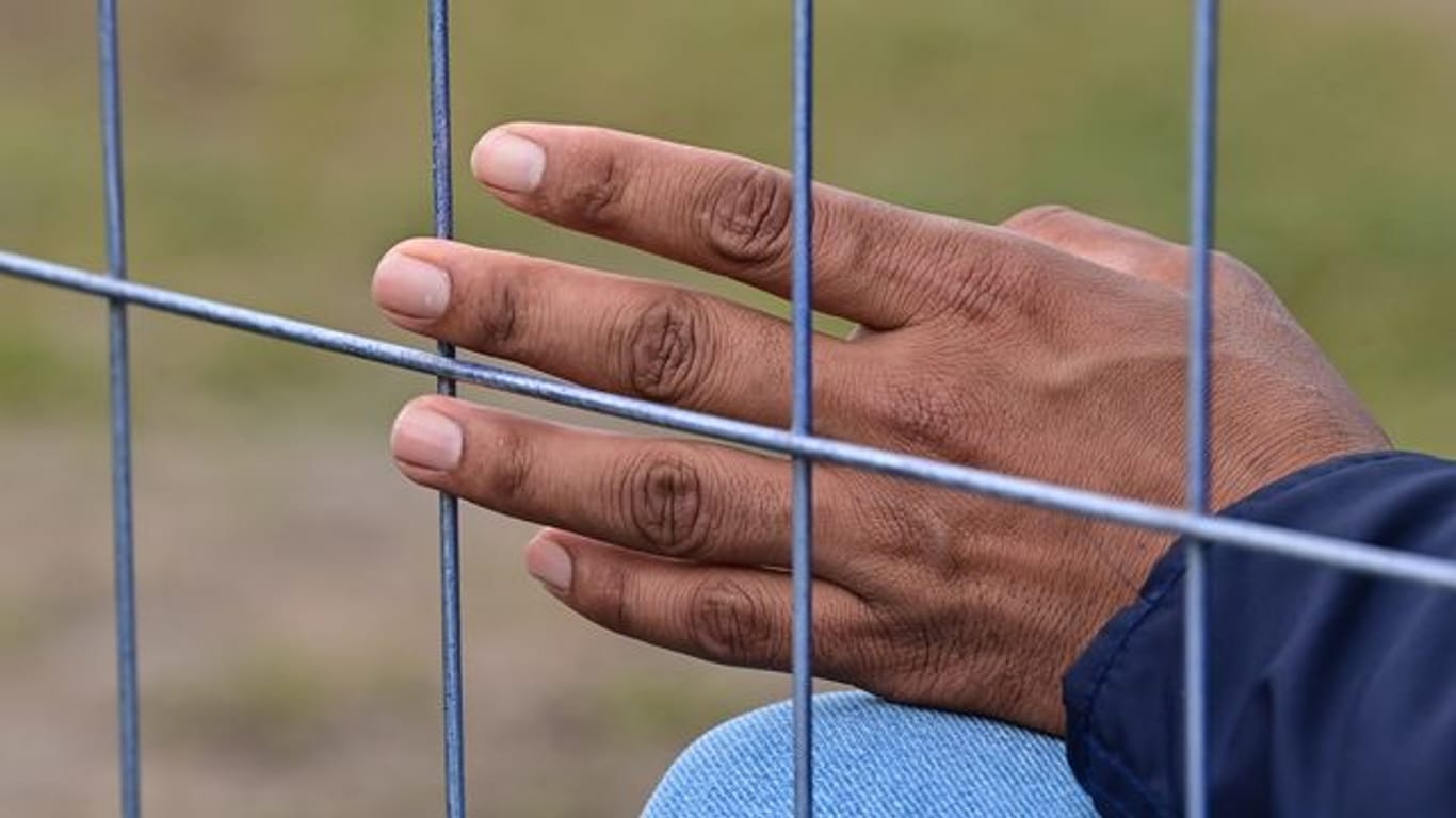 Die Hand eines Flüchtlings am Zaun einer Erstaufnahmeeinrichtung für Asylbewerber.