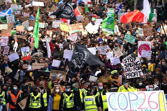 Demonstrierende ziehen mit Flaggen und Schildern durch die Straßen von Glasgow.