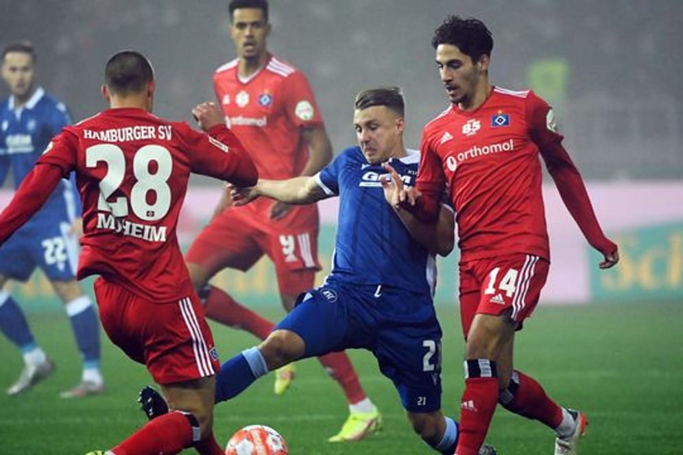 Der Karlsruher Marco Thiede (M) kämpft mit den Hamburgern Miro Muheim (l) und Ludovit Reis um den Ball.