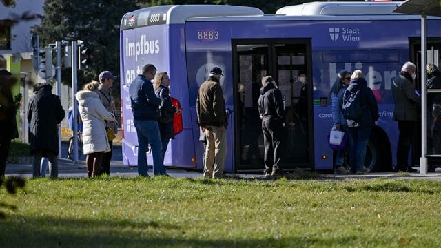 Impfwillige stehen vor einem Impfbus in Wien.