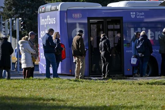 Impfwillige stehen vor einem Impfbus in Wien.