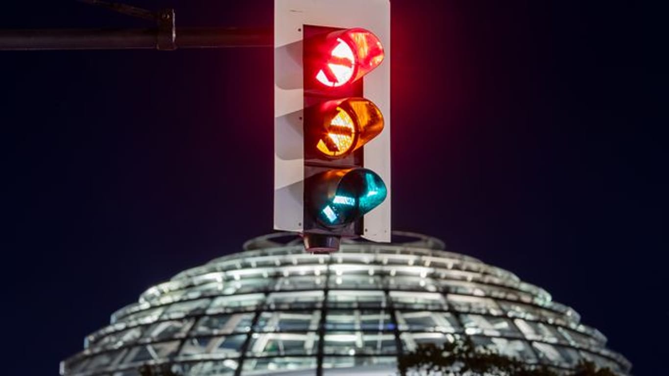 Rot-gelb-grün - eine Ampel leuchtet vor der Kuppel des Reichstagsgebäudes (in einer Langzeitbelichtung) in allen drei Phasen.