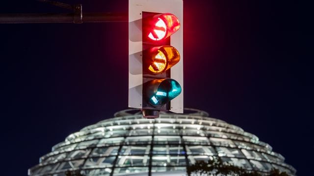 Rot-gelb-grün - eine Ampel leuchtet vor der Kuppel des Reichstagsgebäudes (in einer Langzeitbelichtung) in allen drei Phasen. Rot-gelb-grün - eine Ampel leuchtet vor der Kuppel des Reichstagsgebäudes (in einer Langzeitbelichtung) in allen drei Phasen.