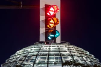 Rot-gelb-grün - eine Ampel leuchtet vor der Kuppel des Reichstagsgebäudes (in einer Langzeitbelichtung) in allen drei Phasen.