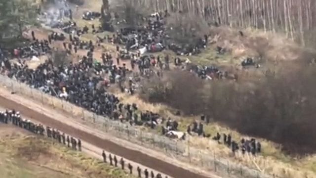 Ein TV-Bild zeigt Migranten auf dem Weg zur belarussisch-polnischen Grenze. Ein TV-Bild zeigt Migranten auf dem Weg zur belarussisch-polnischen Grenze.