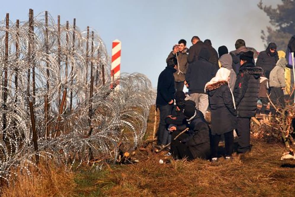 Migranten vor einem Grenzzaun aus Stacheldraht an der belarussisch-polnischen Grenze bei Grodno Grodno.